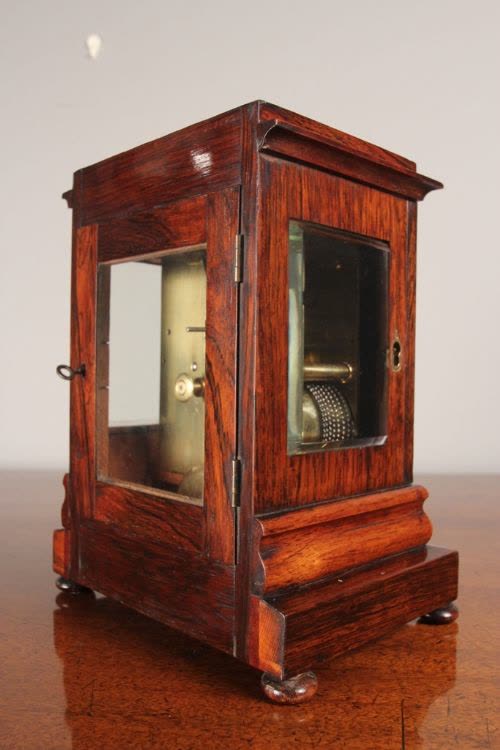 Rear three-quarter view of the rosewood four-glass library clock displaying internal movement and fusee chain