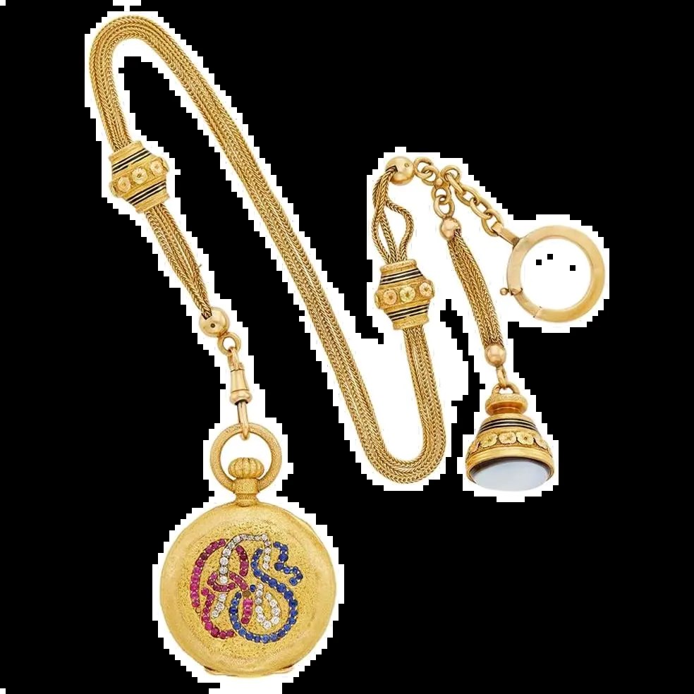 Rear view of the textured 18k gold pocket watch displaying the gem-set monogram, accompanied by a triple-strand foxtail chain and agate fob